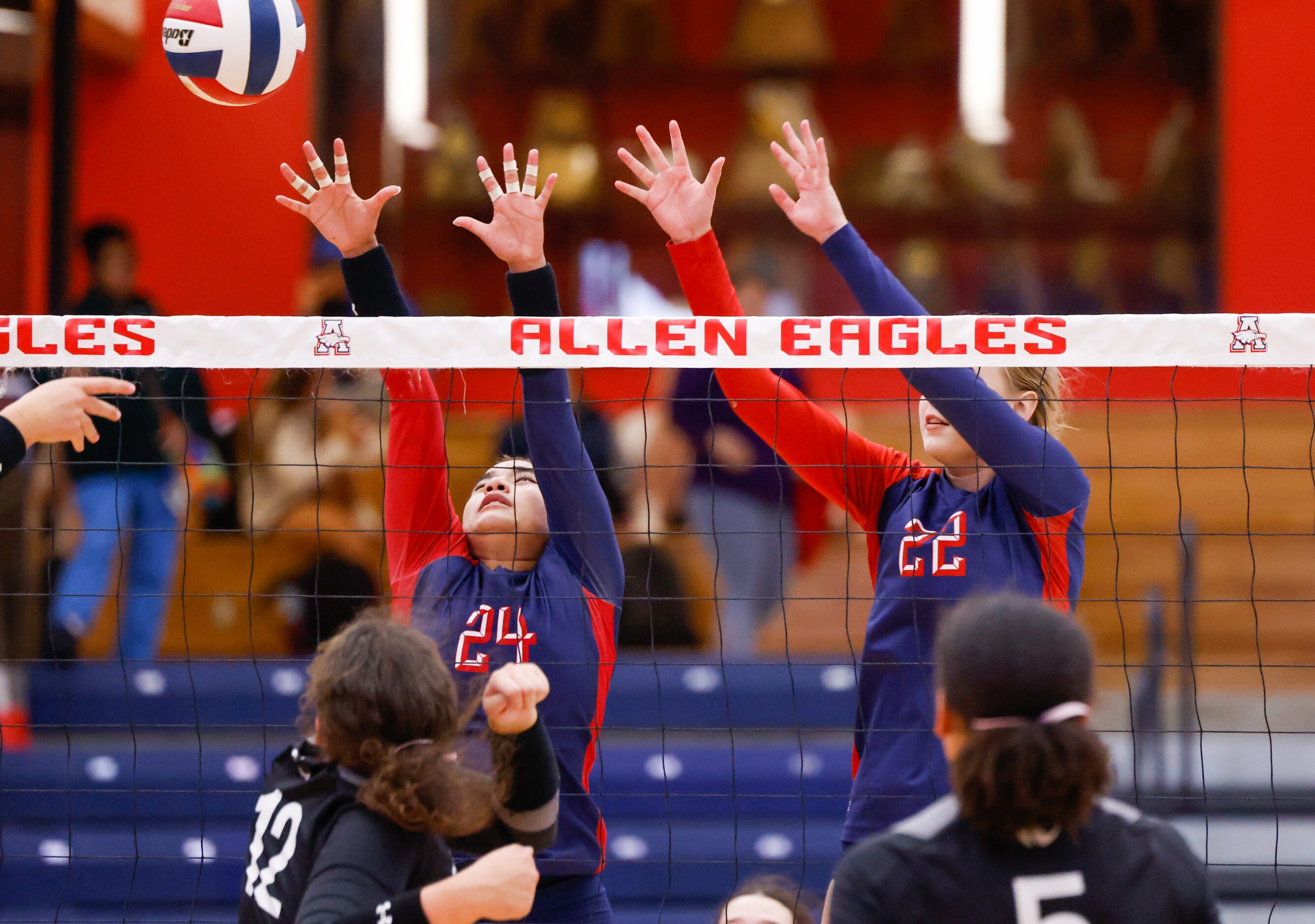 Allen junior Sophia Wilson (24) and junior Zofia Formella (22) leap to block against a...