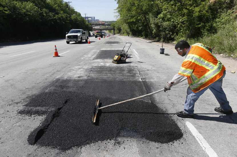 Dallas Street Services employee Gary Langley works to fix a road on Harry Hines Boulevard.