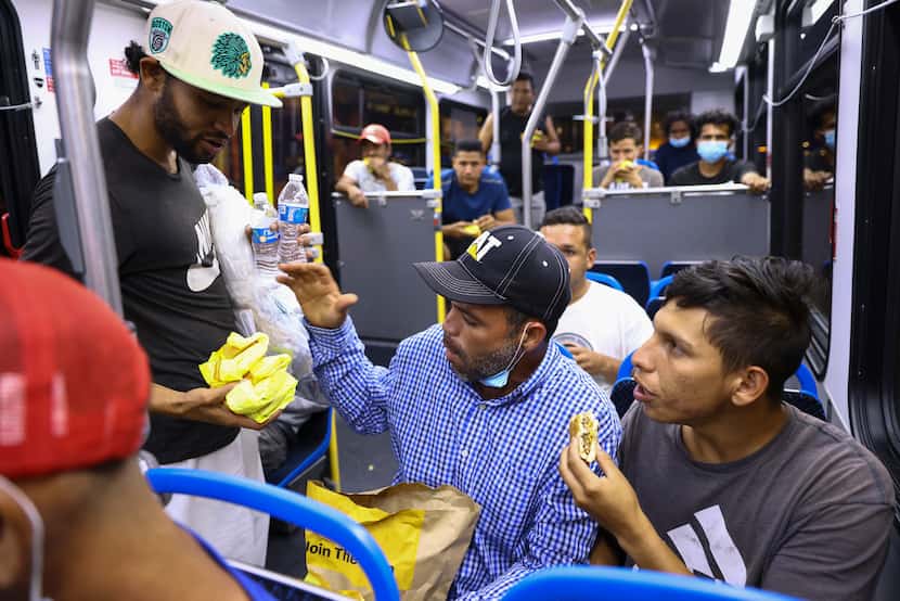Migrants share food as they load a bus to take them to a refugee center outside Union...