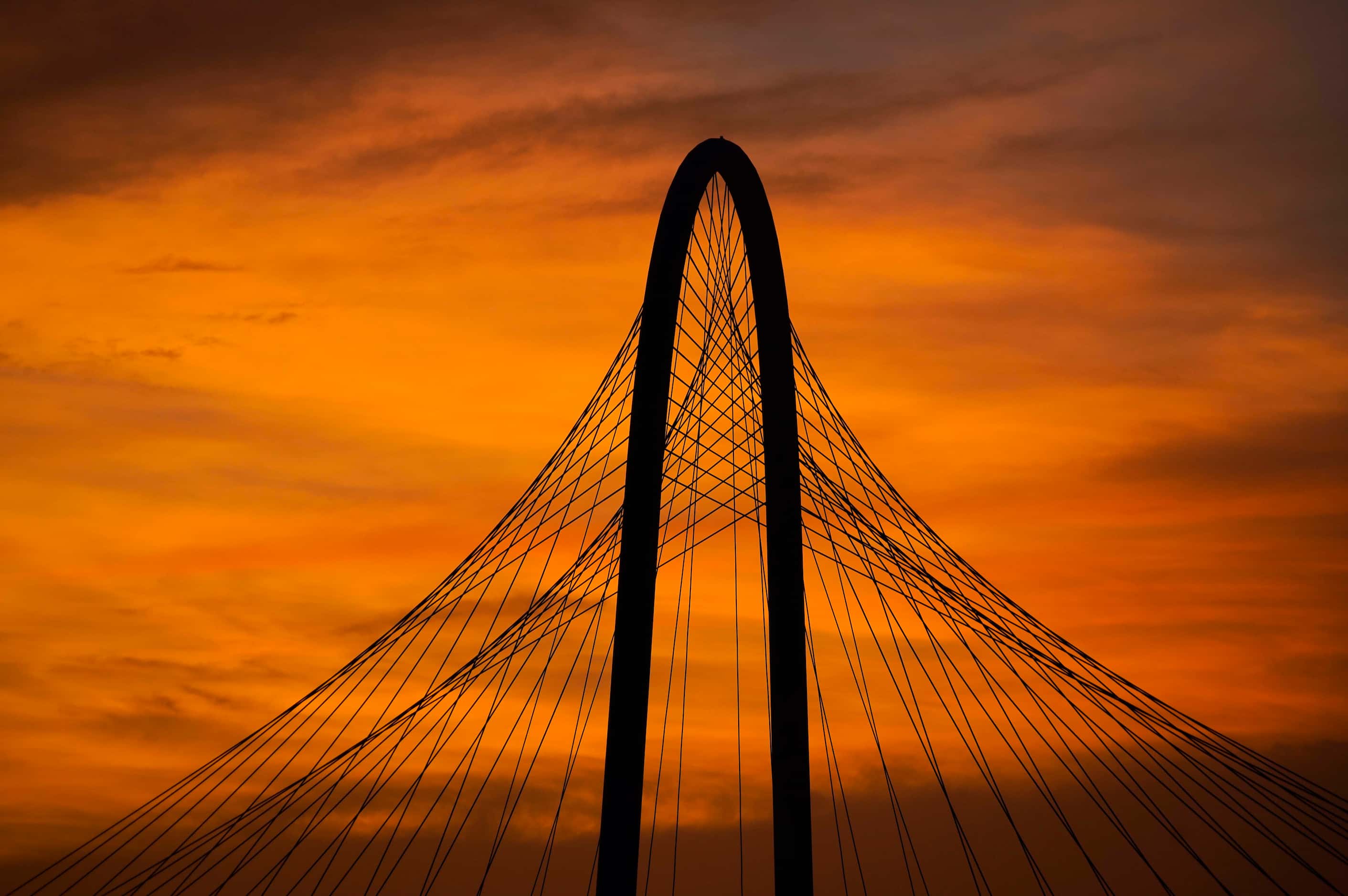 The lingering colors of sunset silhouette the Margaret Hunt Hill Bridge on Tuesday, June 30,...
