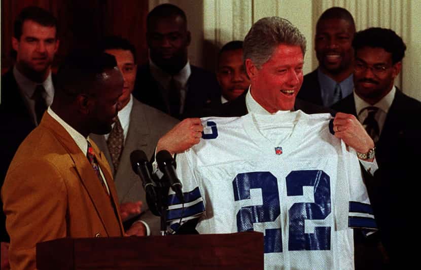 US President Bill Clinton (R) holds a Dallas Cowboys jersey presented to him by running back...