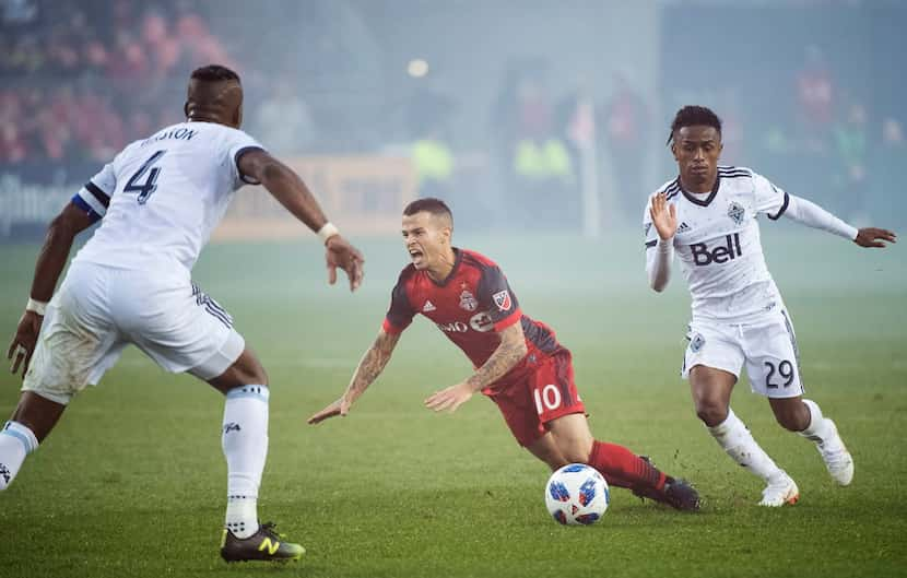 Toronto FC forward Sebastian Giovinco (10) gets tripped up by Vancouver Whitecaps forward...