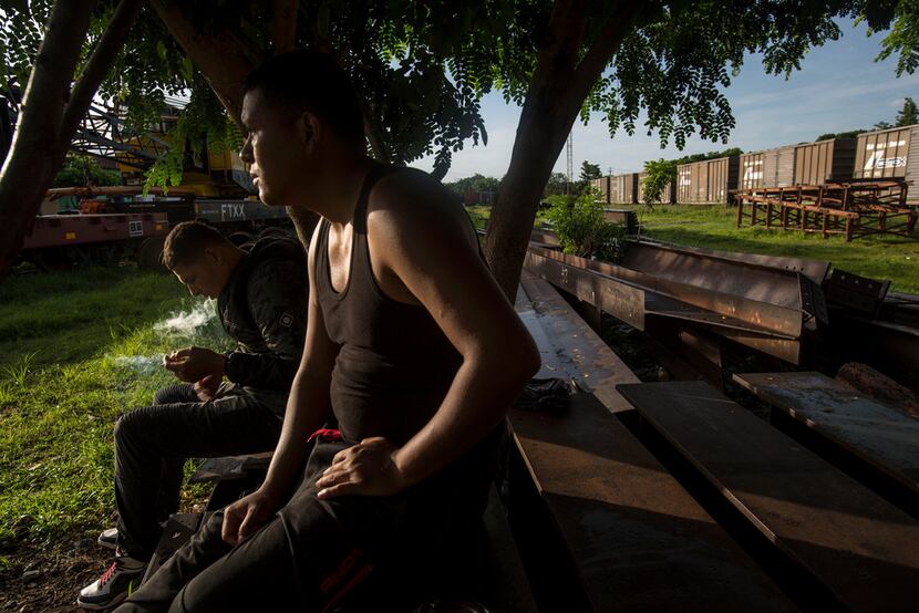 Honduran migrants sit on discarded rail tracks as they wait for a train heading north, in...