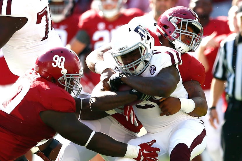 TUSCALOOSA, AL - OCTOBER 18:  Tra Carson #21 of the Texas A&M Aggies is tackled by Jarran...