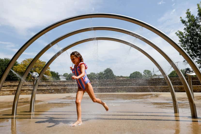 Ellie Dyer, 9, ran through an overhead sprinkler on the splash pad at Al Ruschhaupt Park in...