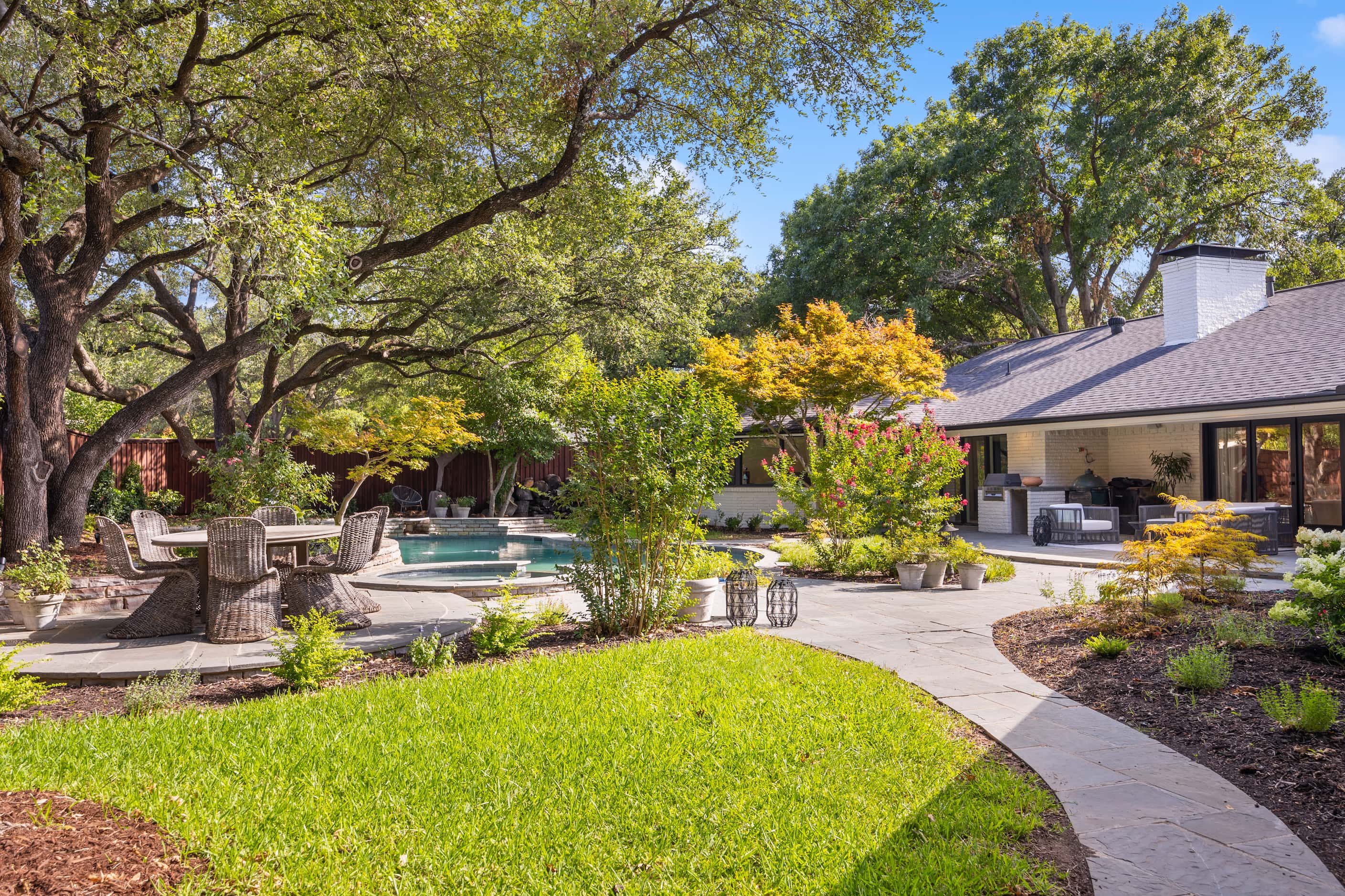 Backyard with pool and multiple outdoor seating areas at back of midcentury ranch-style home