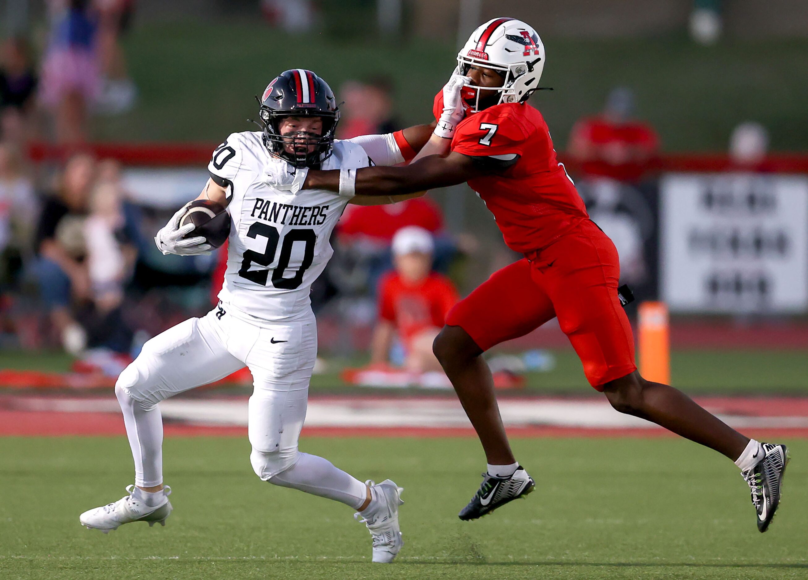 Colleyville Heritage kick returner Bryson Burgess (20) gives a stiff arm to Argyle defensive...