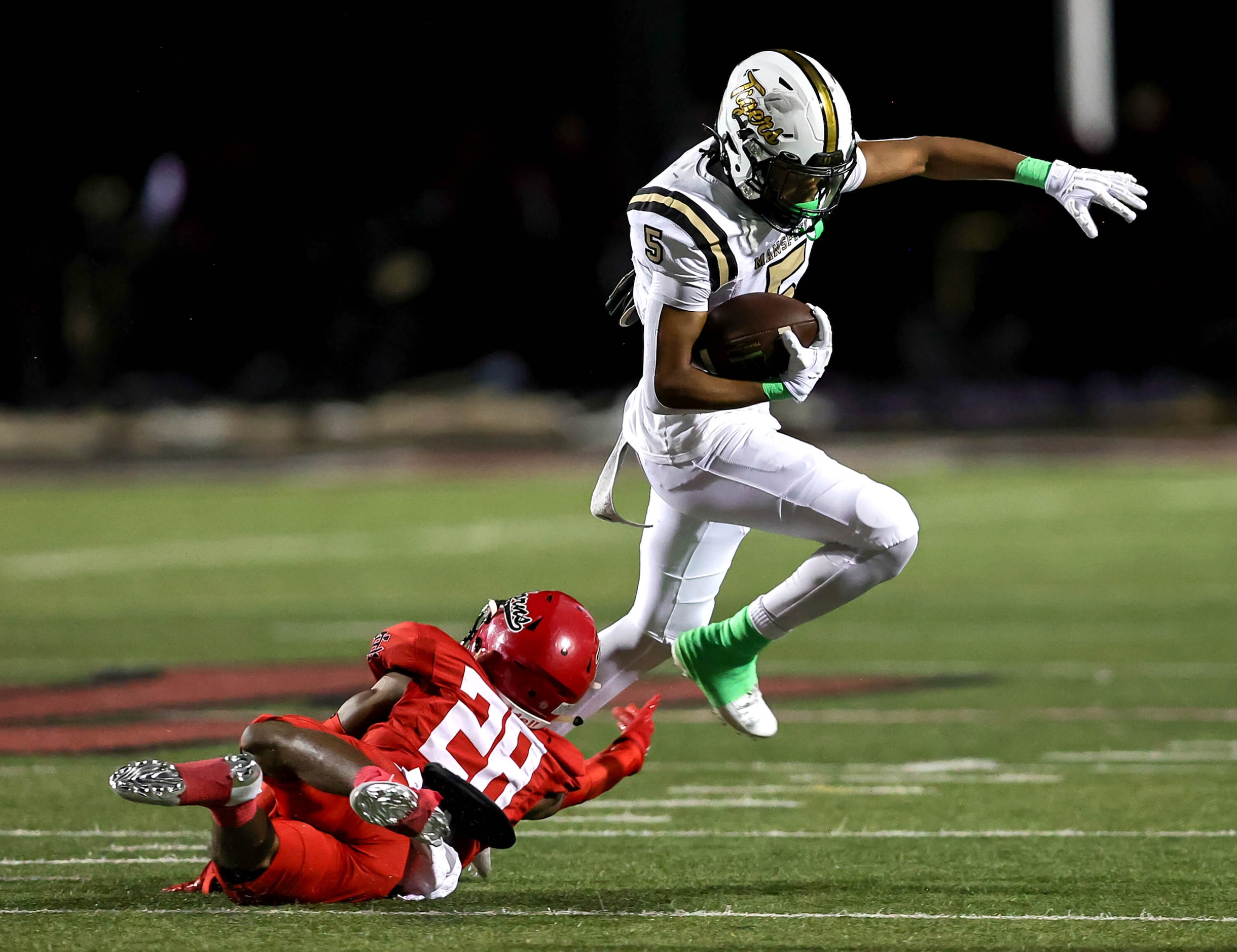 Mansfield running back Marquise Hubbard (5) leaps over Cedar Hill strong safety Michael...