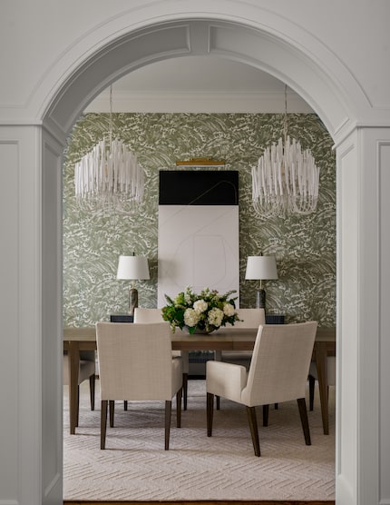 Dining room with patterned green wallpaper, dual chandeliers over the tale and a cream rug