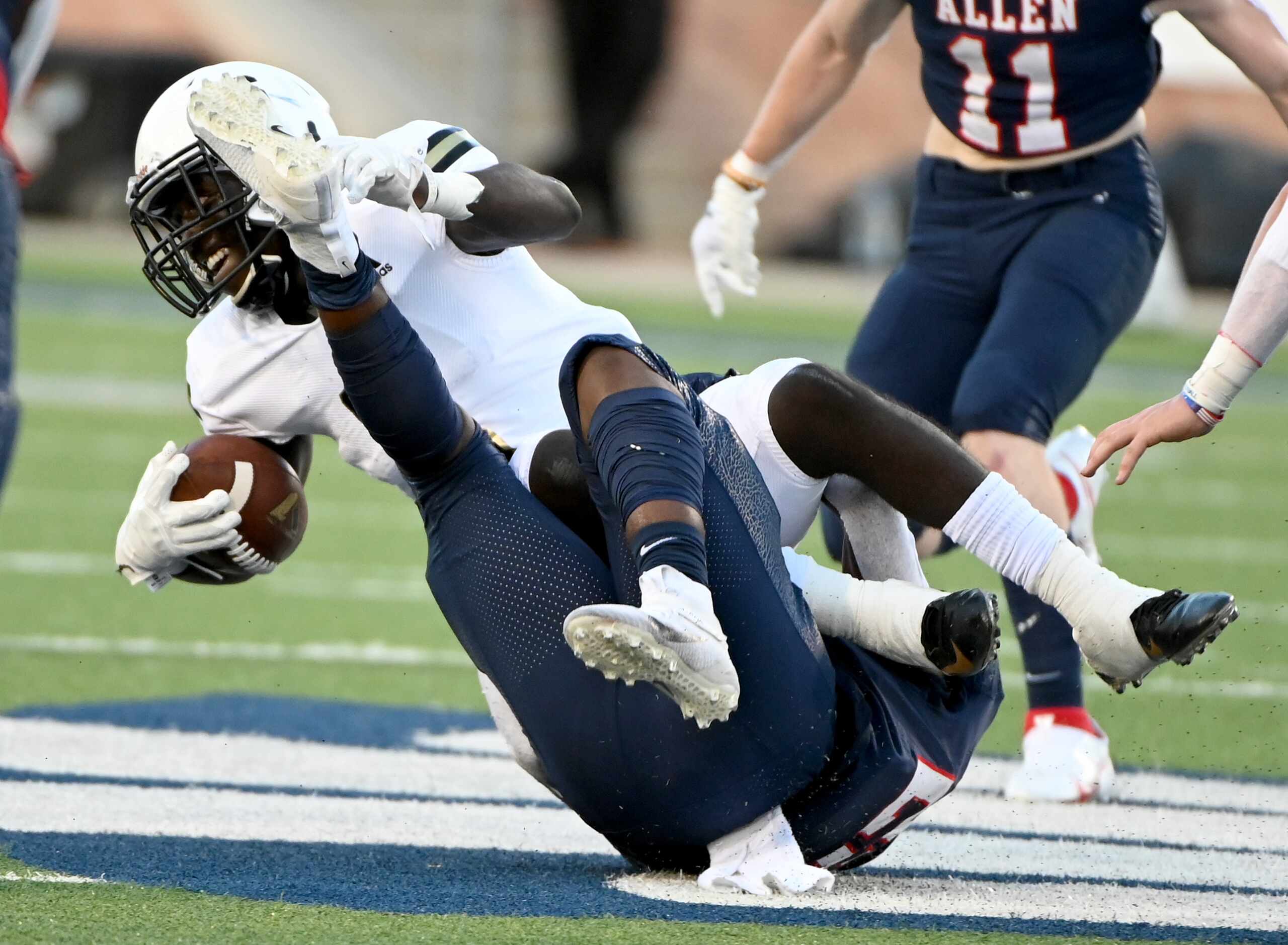 Plano East Ismail Mahdi, in white, is tackled by Allen’s Michael Momoh in the first half...
