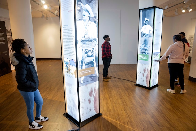 People stop to read the informative pillars in the “Black Cowboys: An American Story”...