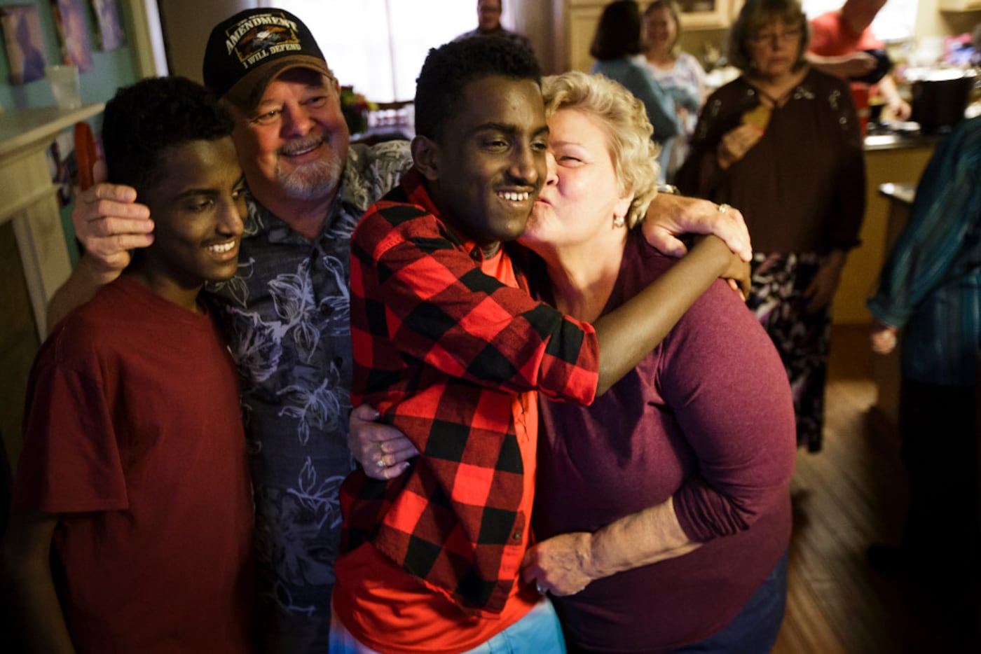 Marcos Bogale (center) gets a kiss from Linda Keylon as his twin Tamirat gets a hug from...
