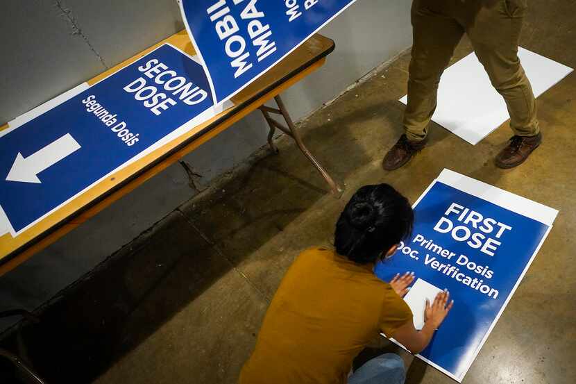 Workers prepare signs that will direct lines of people receiving either their first of...