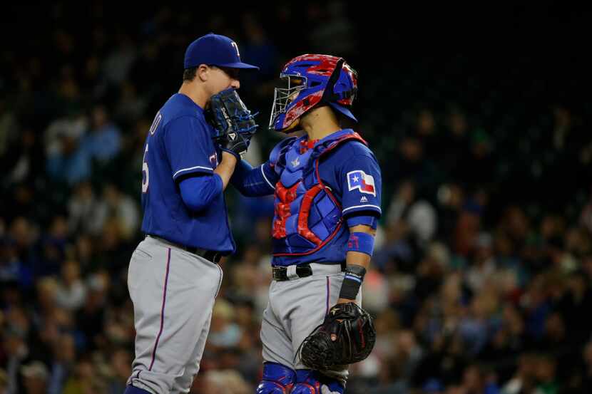 Texas Rangers catcher Robinson Chirinos, left, talks with starting pitcher Derek Holland,...