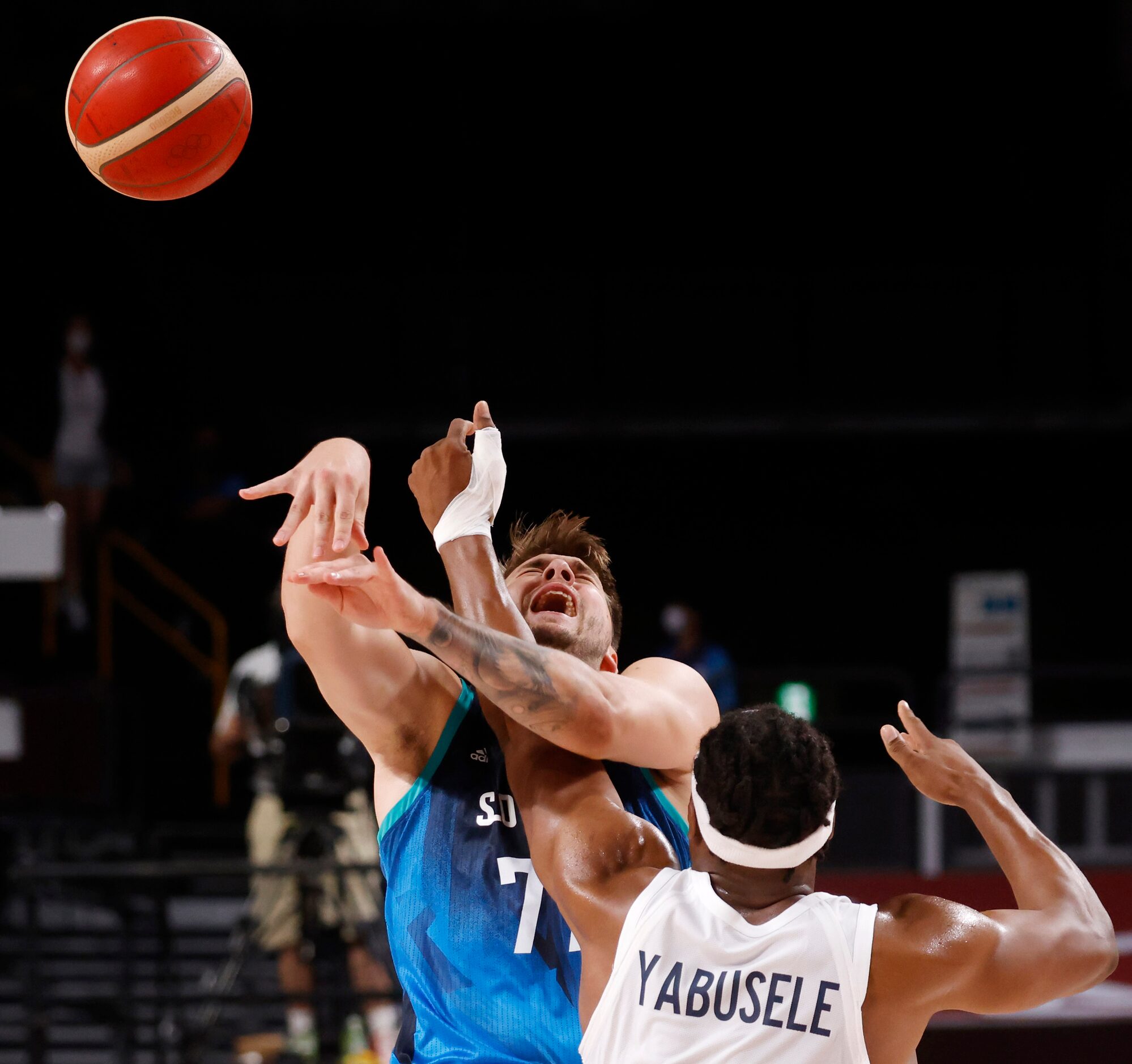 Slovenia’s Luka Doncic (77) passes the ball as he is hit by France’s Guerschon Yabusele (7)...