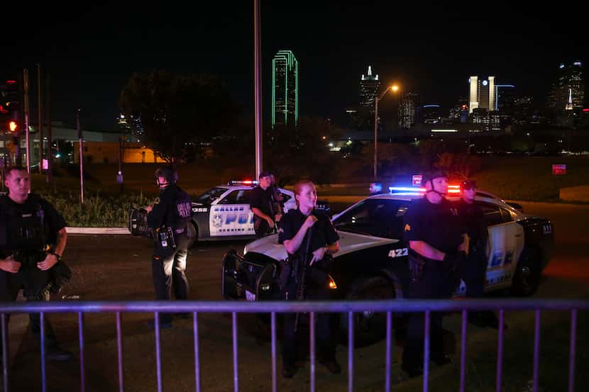 Police officers watch as demonstrators march from the Dallas Police Department headquarters...