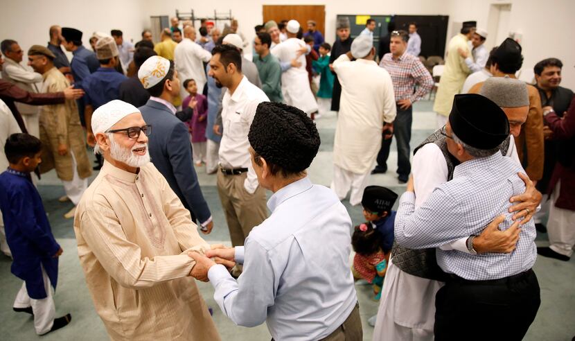 Ahmadiyya Muslim Community Dallas members Shamim Ahmad (left) and Talha Moktader shake hands...