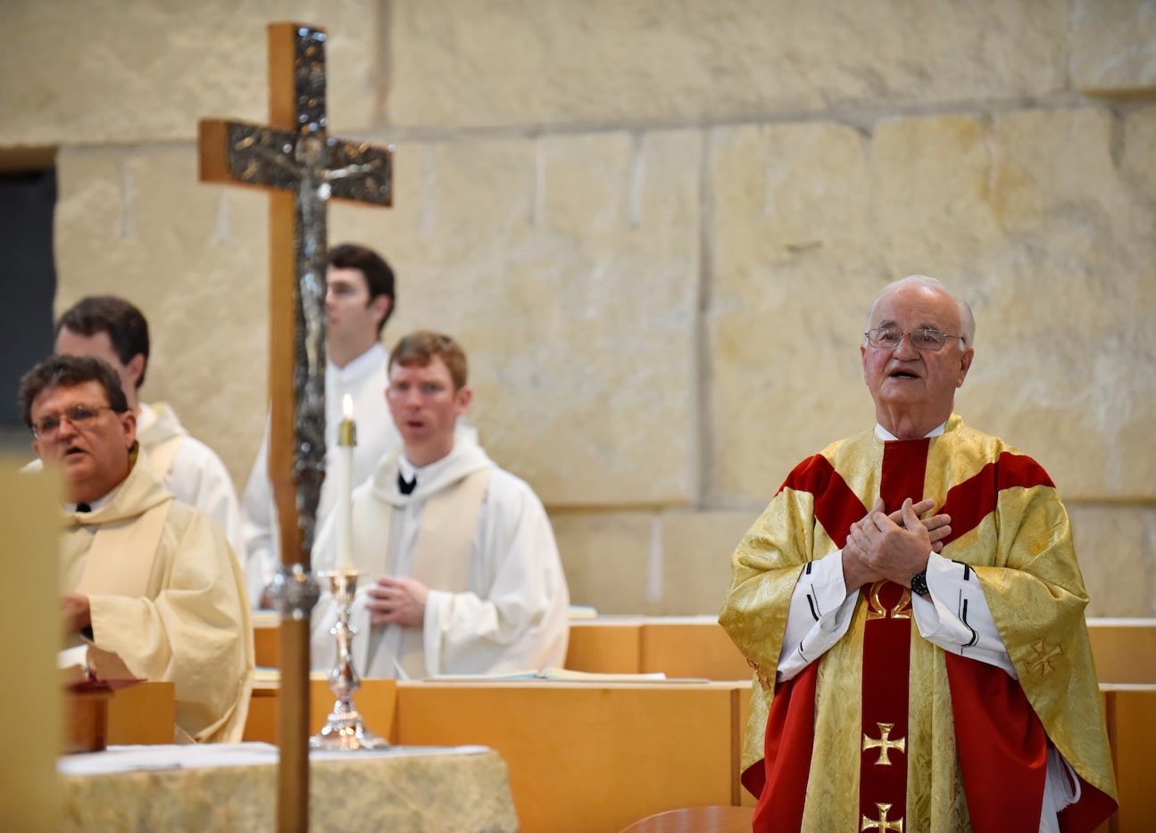 The Rev. Bernard Marton (right) crossed his hands over his chest during prayer as he...