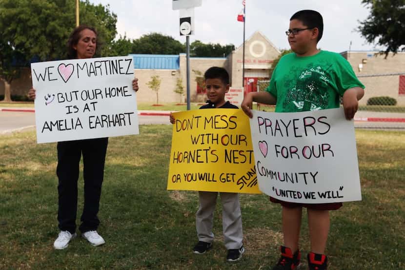 From left,  Joann Lopez,  Jamir Barba, 9,  and Jonathan Lopez, 11, hold signs outside Eladio...