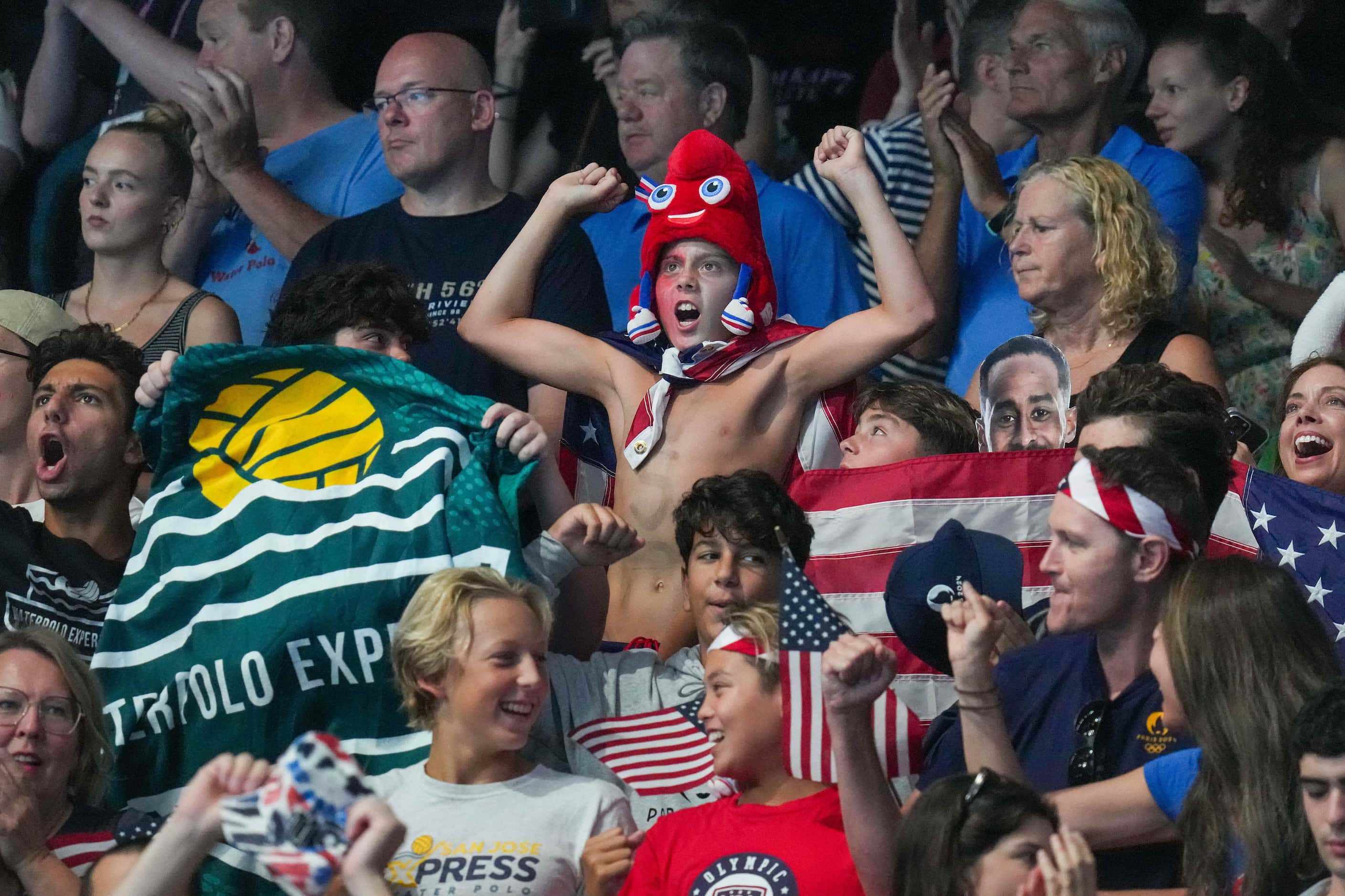 Fans cheer for the United States during a men’s water polo semifinal against Serbia at the...