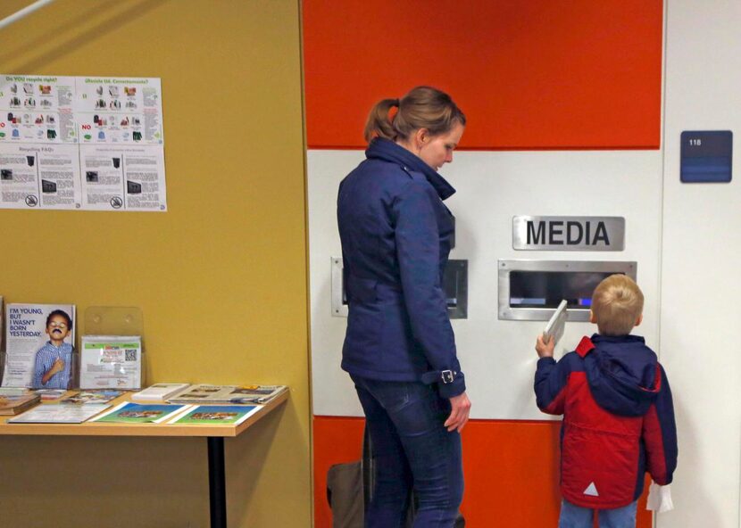 
Declan Boyd, 4, returns a movie to the library with his mother, Michelle Boyd, at White...