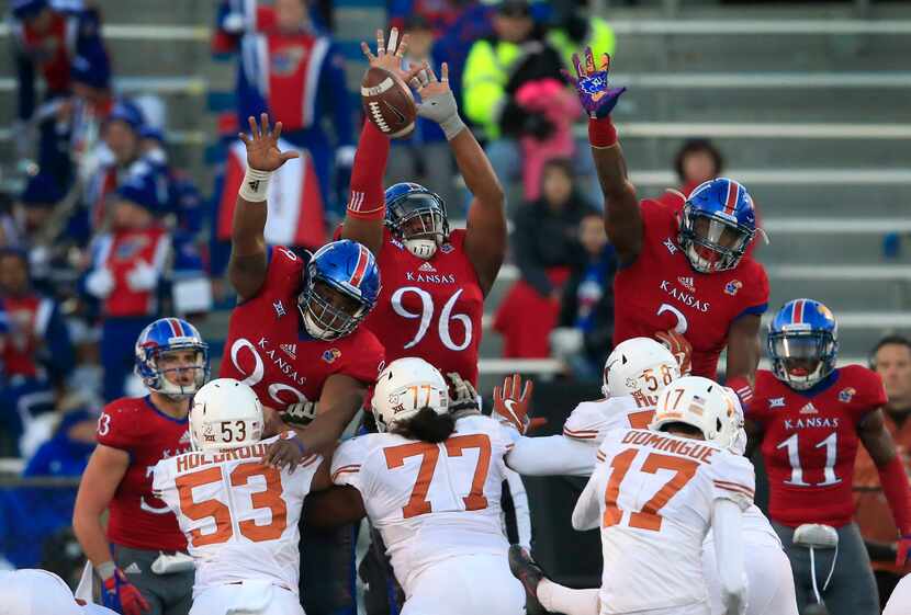 Texas place kicker Trent Domingue (17) kicks a point after over Kansas defensive tackles...