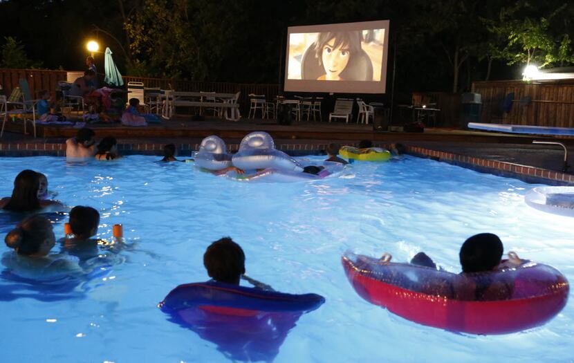 Swimmers gather around the screen at Movie Night at The Texas Pool. The feature was Big Hero...