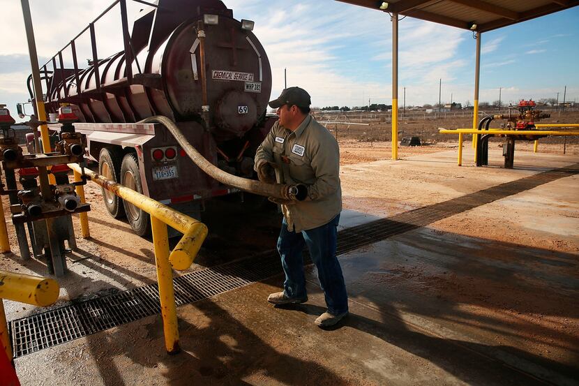 An oilfield worker fills his truck with water at a filling station before heading to a...