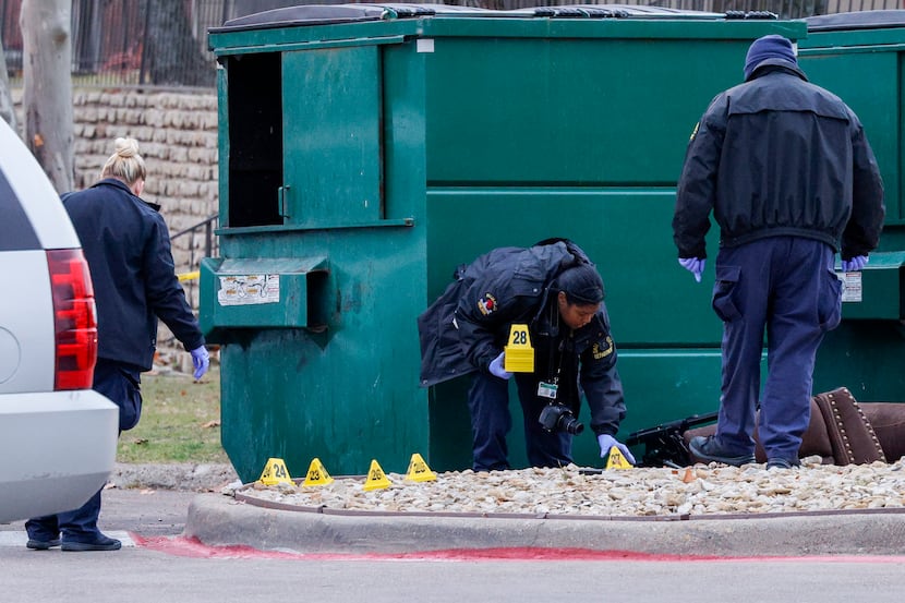 Dallas crime scene technicians place evidence markers at the scene where a Dallas police...