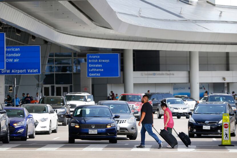 Airline passengers walk the drop-off and pick up area at Dallas-Fort Worth International...