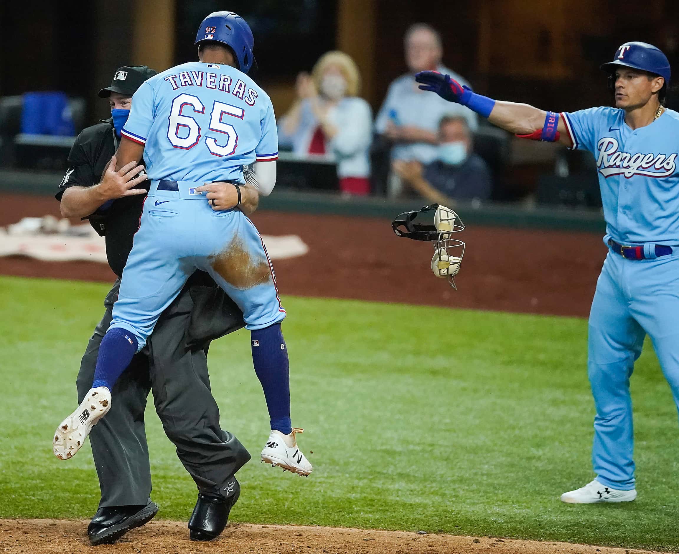 Texas Rangers center fielder Leody Taveras collides with umpire Marvin Hudson after crossing...