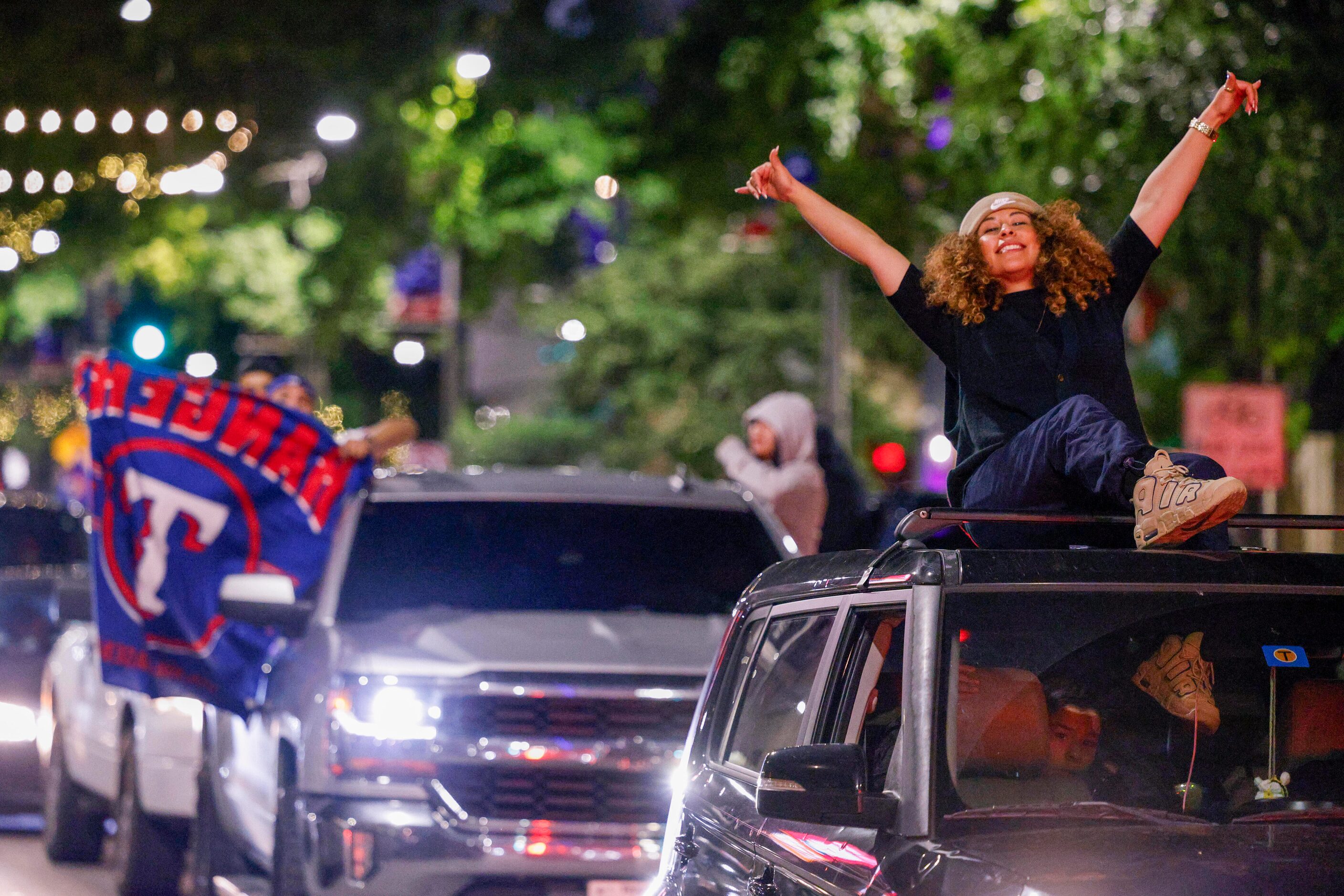 Ileana Soto sits on the roof of her car as people celebrate the Texas Rangers World Series...