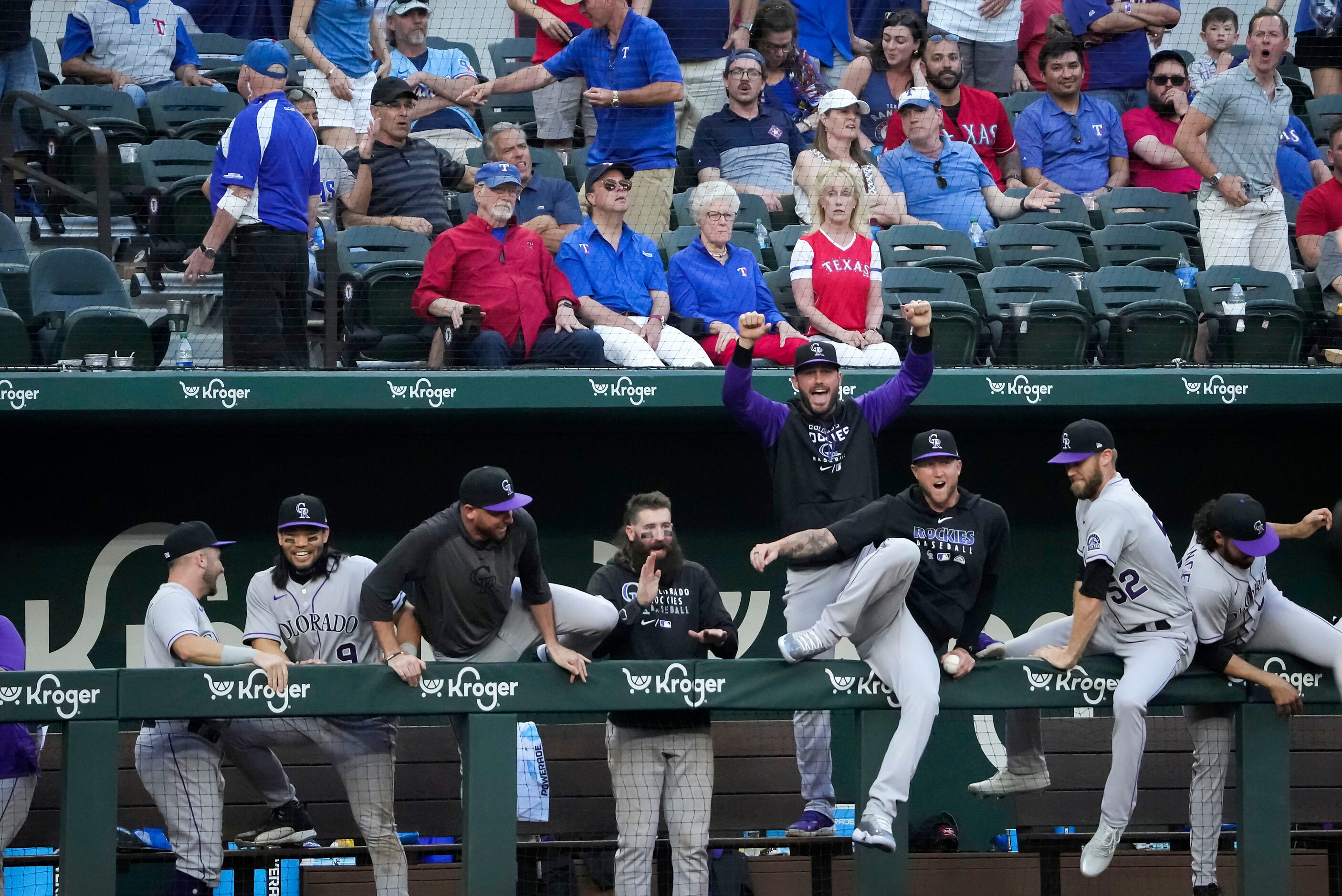 Colorado Rockies players tumble over the dugout rail in celebration after a video replay of...