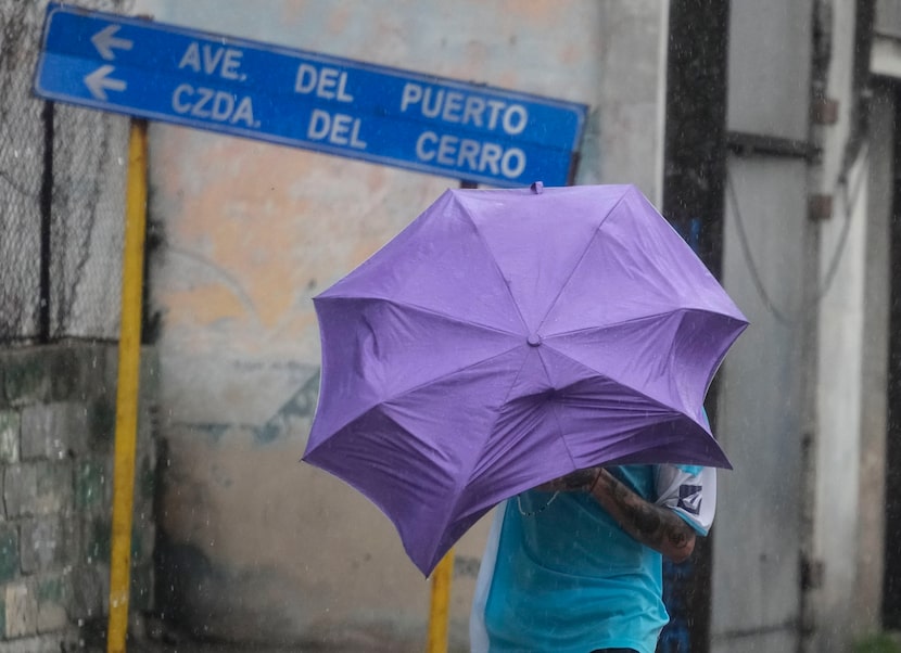 Un hombre camina entre el viento y la lluvia provocados por el huracán Rafael en La Habana,...