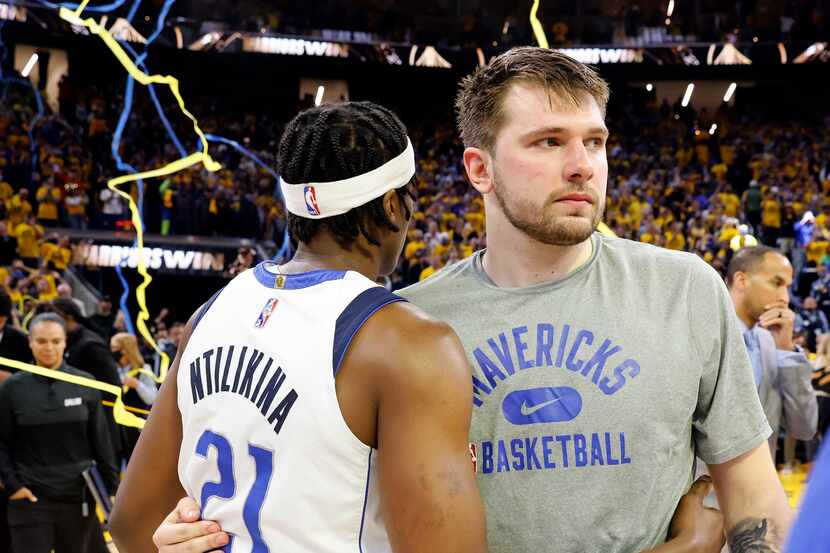 Dallas Mavericks guards Luka Doncic (77) and Frank Ntilikina (21) hug following their Game 5...