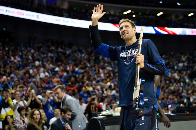 Dallas Mavericks forward Dirk Nowitzki waves to the crowd after being presented with a...