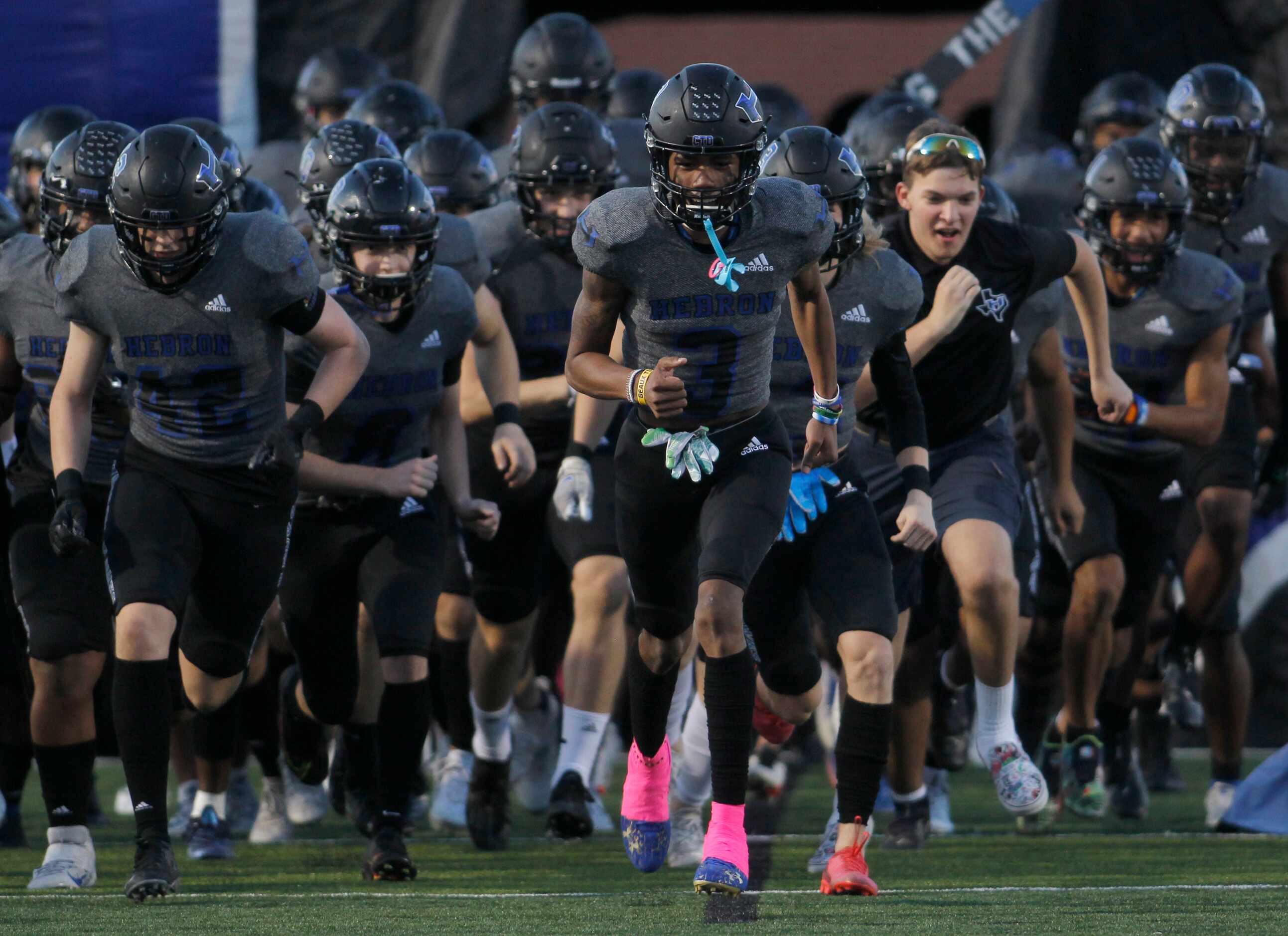 Hebron Hawks players race onto the field prior to the opening kickoff of their game against...