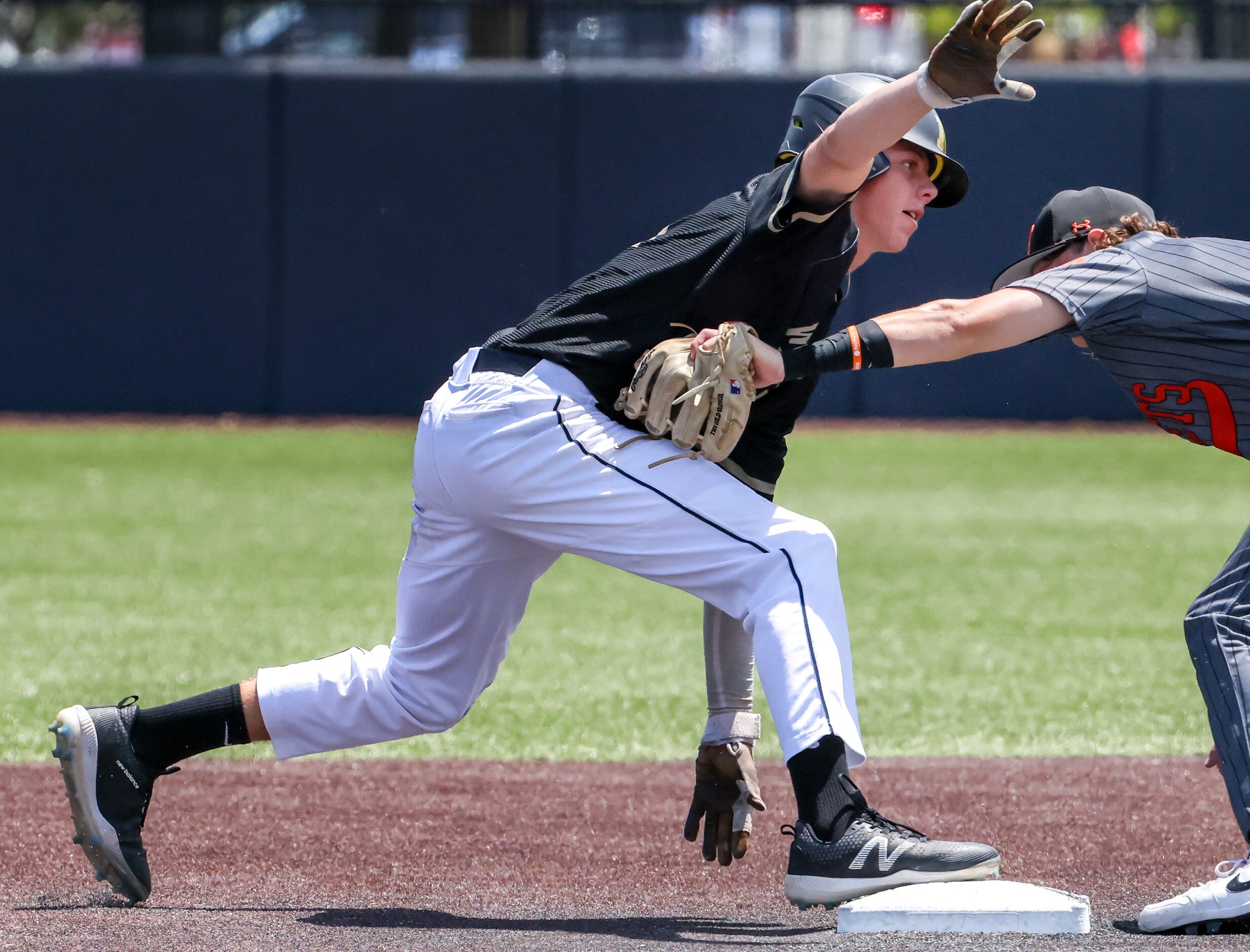 Mansfield left fielder Jaxson Wylie (21, left) places a foot back on second base during an...