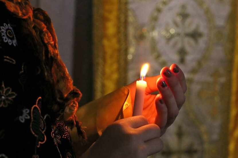 An Iraqi Christian girl holds a candle as she attends a mass at the Church of the Immaculate...