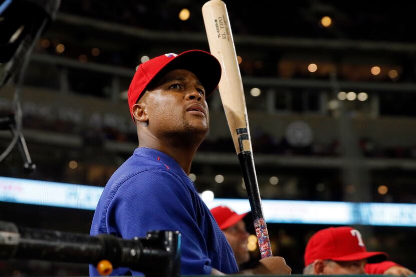 Texas Rangers' Adrian Beltre stands at the top of the dugout gripping a bat as he watches a...