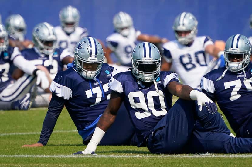 Dallas Cowboys defensive end DeMarcus Lawrence (90) stretches with teammates Trysten Hill...