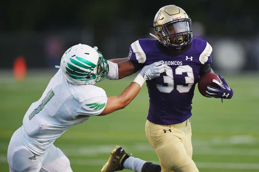 Denton running back Xylohn Posey (33) stiffarms Lake Dallas defender Nick Cagnetto (1)...