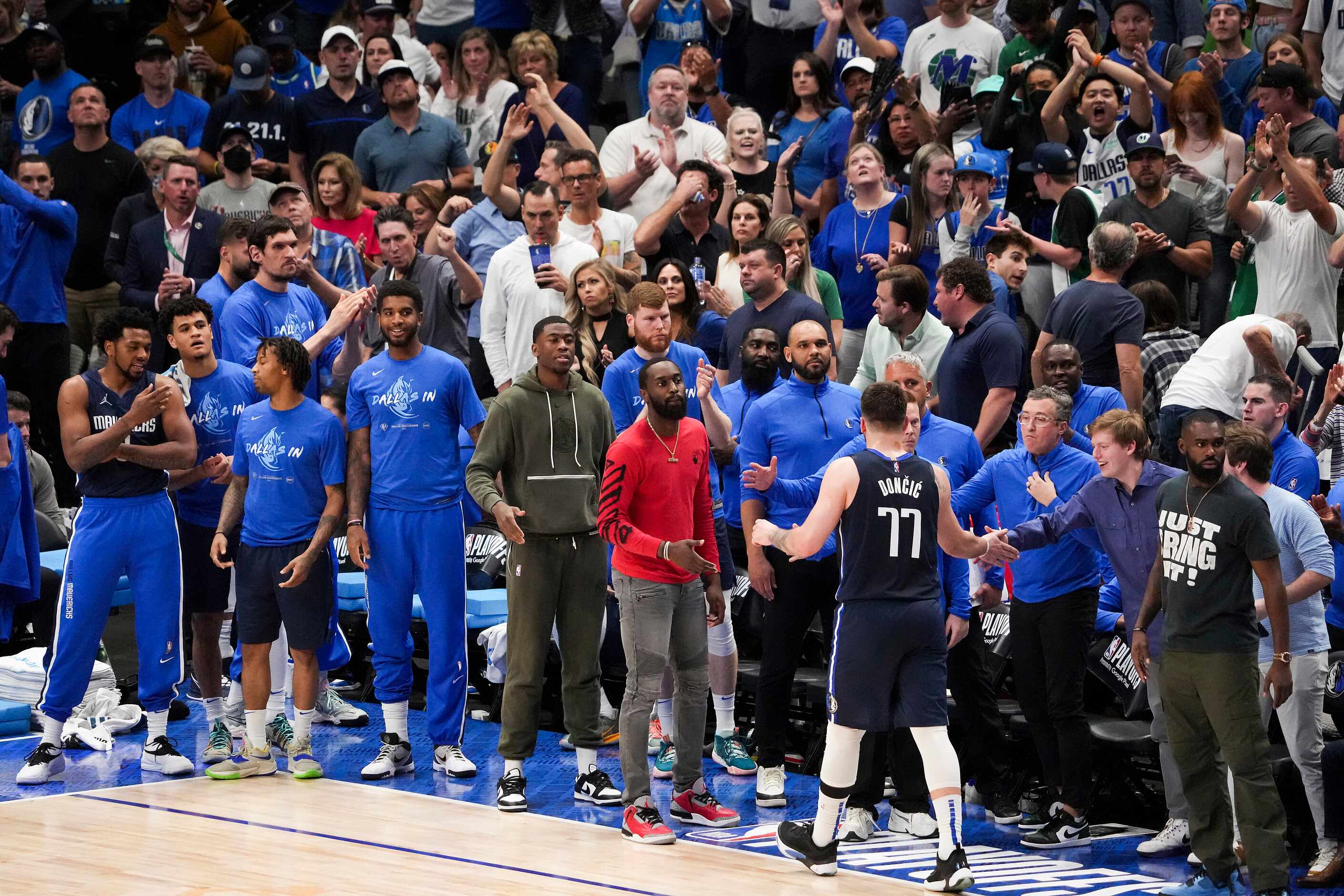 The Dallas Mavericks bench and fans applaud guard Luka Doncic (77) as he comes out of the...