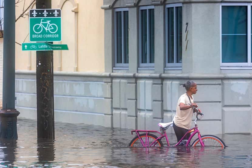 A cyclist pedals along a flooded street during a major thunderstorm, Wednesday, April 10,...