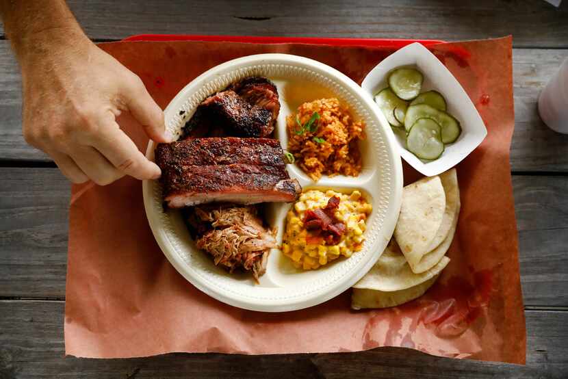 Pork ribs, pulled pork and brisket are served with a side of jalapeño corn, Spanish rice...