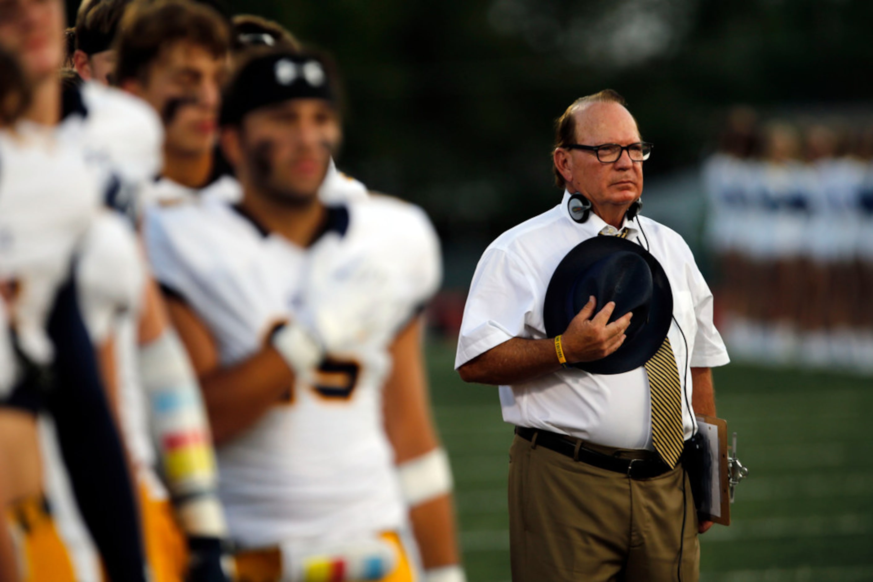 Highland Park coach Randy Allen and his team stand at attention during the national anthum...