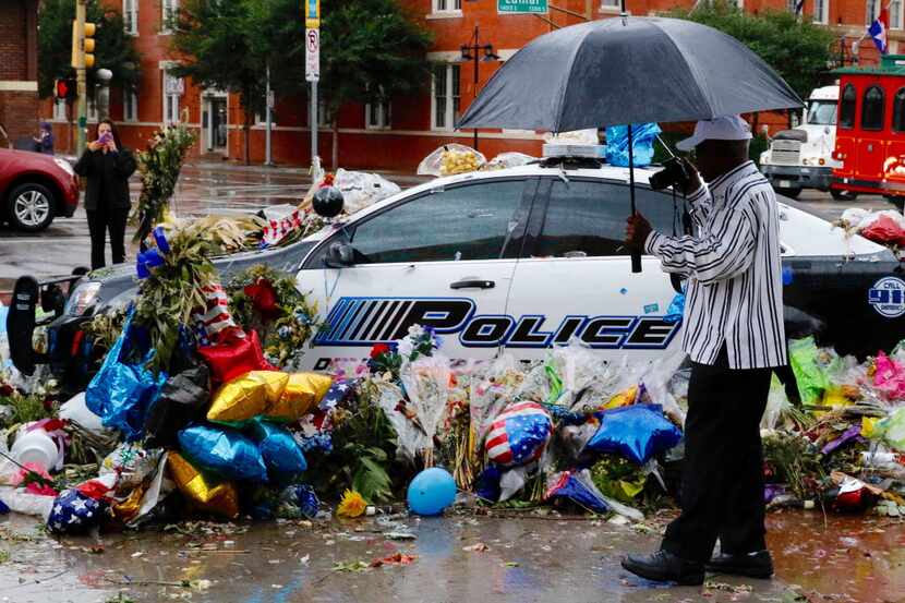 Thomas Freeney of Dallas takes photos of the memorial at the Dallas police headquarters in...