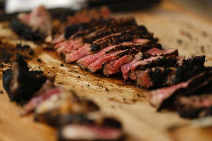 Once the steak is removed from the coals and allowed to rest, chef Tim Byres carves it into...