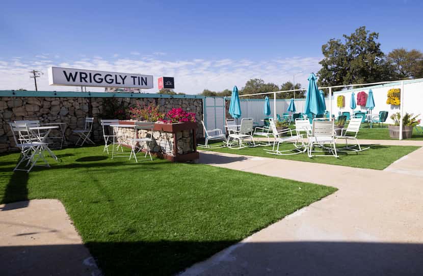 The outdoor patio at Wriggly Tin has turquoise chairs and tall fences. 