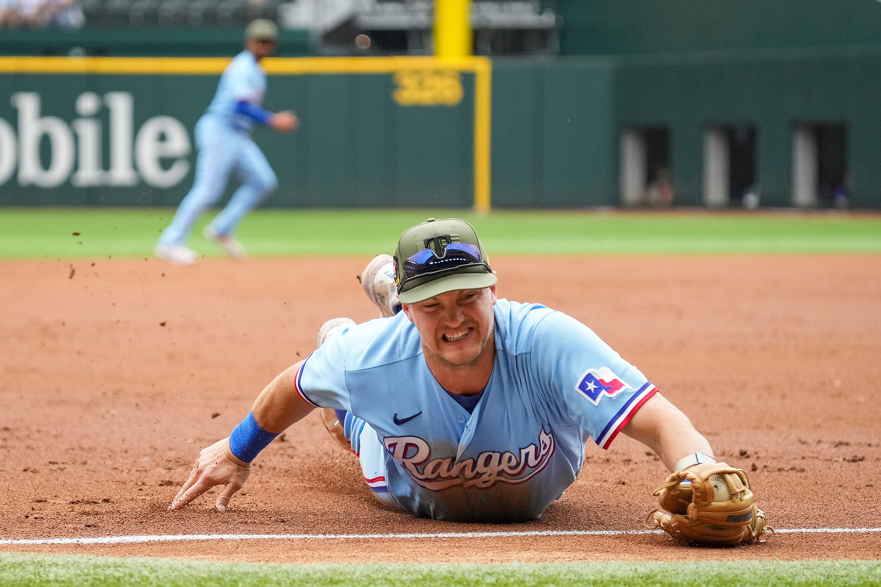 Texas Rangers third baseman Josh Jung makes a diving stop on a grounder off the bat of...